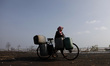 A woman carry water gallons using bicycle to get clean water from the mosque water tank, w...