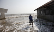 A man stands on the sandbag wave barrier beside his house in Simonet village, northern coa...