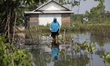 A woman walking through the tidal floods in Simonet village, northern coast of Pekalongan...