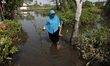 A woman walking through the tidal floods in Simonet village, northern coast of Pekalongan...