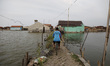 Villagers do their activity in their neighborhood surrounded by tidal floods in Bandengan...