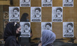 Iranian women stand in front of electoral posters out of a campaign center for the conserv...