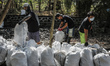 Volunteers of Sungai Watch take part in cleaning river canal from plastic trashes near man...
