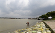 A man baths on the river Ganga with dense cloud formations in the background in Kolkata, I...