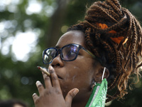 A person lights up a marijuana cigarette as New York City mayoral candidate Paperboy The Prince speaks and sings to a group of people near C...