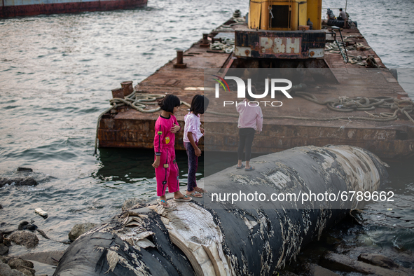 Children playing among the wreckage of a ship at the shore in the north of Indonesia's capital Jakarta on 8 June 2021. As people around the...