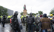 Misak indigenous stand in front of police officers as she protest next to the statue of qu...
