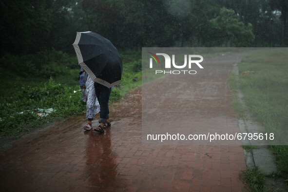 A couple tries to cover them from rain as they hold an umbrella at a park in Dhaka, Bangladesh on June 11, 2021. 