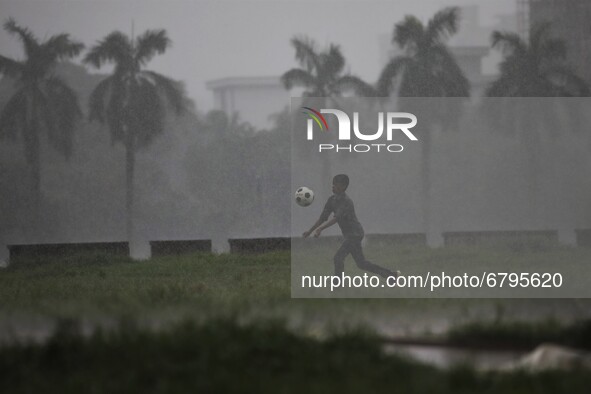 A boy plays football during rain at a park area in Dhaka, Bangladesh on June 11, 2021. 