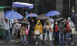 Passers-by cover themselves from the rain with umbrellas and raincoats in the Historic Cen...