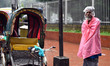 Ricksha puller Lal Mia standing beside the road waiting for passengers during rain in Dhak...