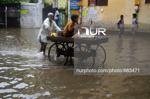 An Indian vendor transport  his child in a cart in  the waterlogged street due to heavy rain in Kolkata, India on  Friday, July 10, 2015. 
