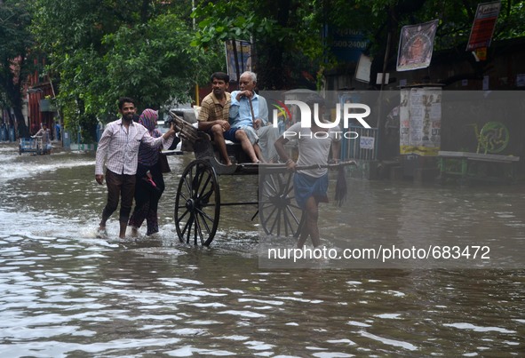 An Indian rickshaw puller transports passengers in the waterlogged street due to heavy rain in Kolkata, India on  Friday, July 10, 2015. 