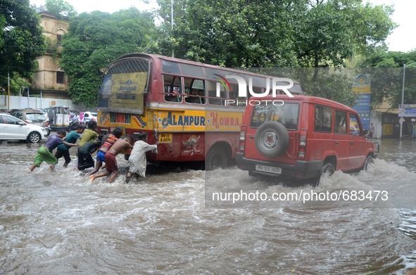Indian street children  pushing the breakdown  bus  in the waterlogged street due to heavy rain in Kolkata, India on  Friday, July 10, 2015....