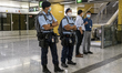 Police officers stand guard on the platform as the first train of the Tuen Ma Line departs...