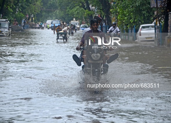 Indian young  people enjoy the bike ride  in  the waterlogged street due to heavy rain in Kolkata, India on  Friday, July 10, 2015. 