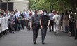 An Iranian young man (R) wearing a protective face mask and a face shield walks with his f...