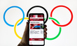 Tokyo 2020 Olympics official website is displayed on a mobile phone screen photographed wi...