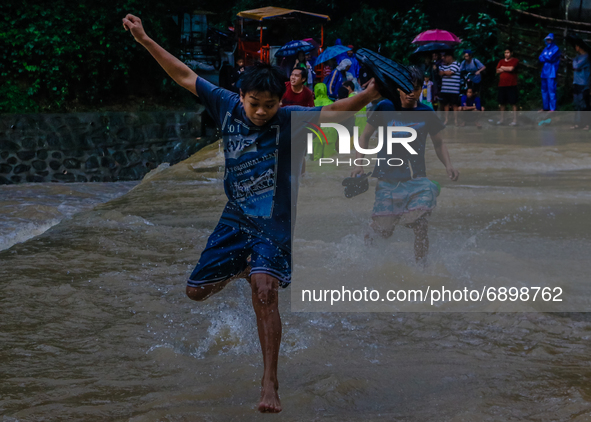 Residents of Calawis, Antipolo City in Philippines are struggling to pass through on an overflowing river due to intensified southwest monso...