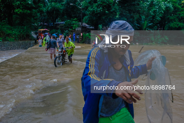 Residents of Calawis, Antipolo City in Philippines are struggling to pass through on an overflowing river due to intensified southwest monso...