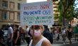 A protester holds a placard reading ' Ignorant µN, prudent Yes, not hot children's vacinat...