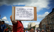 A man shows a placard reading 'The world won't be destroyed by those who do bad, but those...
