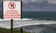 Multi-lingual warning sign by a steep cliff beside the Atlantic Ocean in the Dominican Rep...