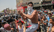 A young demonstrator sitting on another’s shoulders chants anti-government slogans as he g...