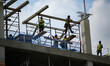 Construction workers watch from the top of a building as thousands of demonstrators march...