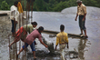 Workers and child labors cement a rooftop in preparation for construction for adding an ad...
