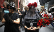 People in costume walk behind artist Anne-Katrin Spiess as she is carried on 5th Avenue in...