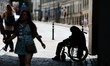 People passes by a man on the wheelchair under the Gate of Dawn in Vilnius, Lithuania on J...