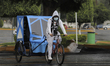 A person on a bicycle in front of the area where a column of the Metro Collective Transpor...