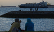 People sitting by the breakwater are pictured with vessels anchored along the southern coa...