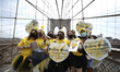 Marchers, some with yellow hearts, walk across the Brooklyn Bridge in remembrance of those...