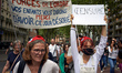 A woman disguised as Marianne stands near a sheet reading 'Policemen, your children will t...