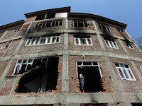 A man stands near the damaged door of the building where according to police a militant was killed during an encounter in south Kashmir's Ku...