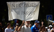A protester holds a sheet reading 'Nor guinea pigs, nor pariahs'. Thousands of  protesters...