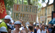 A woman holds a placard reading 'our freedoms pass away'. Thousands of  protesters took to...
