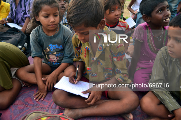 Indian children of slums study in a park,in Allahabad on July 19,2015.Indian students who prepare for competetive exams,educate children in...