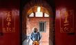An elderly lady with a face mask holds a portion of oranges for worship at a temple, amid...