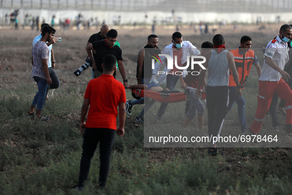 Palestinian protesters evacuate an injured youth amid clashes with Israeli security forces following a demonstration by the border fence wit...