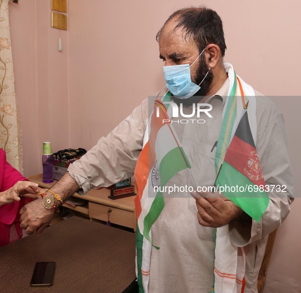 Women tie 'Rakhis' or sacred threads onto the wrist of an Afghan origin Indian resident and hold on India and Afganisthan National Flag  dur...
