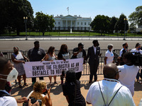 Demonstrators zip-tie their wrists to a fence in front of the White House on August 24, 2021, as part of a civil disobedience protest demand...