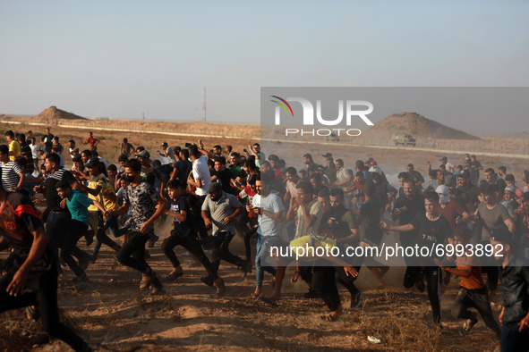 Palestinian demonstrators run from tear gas fired by Israeli security forces during a protest along the border fence, east of Khan Yunis in...