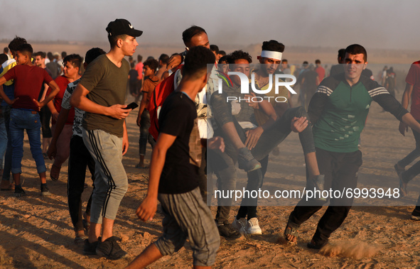 Palestinian protesters carry a wounded young man during a protest in the southern Gaza Strip August 25, 2021. 
 