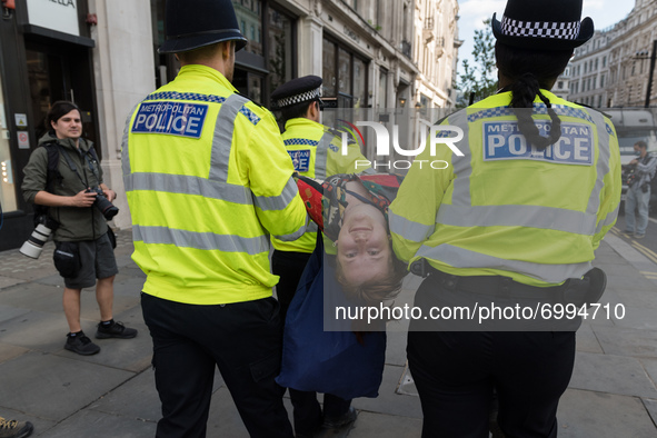 LONDON, UNITED KINGDOM - AUGUST 25, 2021: Police officers carry an environmental activists from Extinction Rebellion who was arrested for bl...
