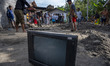 Residents dig in front of their houses to lift motorbikes that were buried in mud after be...