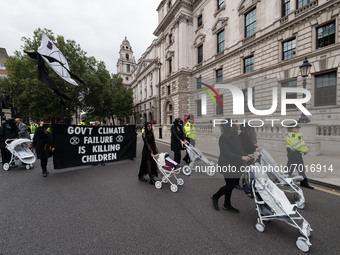 LONDON, UNITED KINGDOM - AUGUST 31, 2021: Activists from Extinction Rebellion dressed in black stage a funeral march with white painted chil...