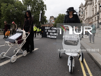 LONDON, UNITED KINGDOM - AUGUST 31, 2021: Activists from Extinction Rebellion dressed in black stage a funeral march with white painted chil...